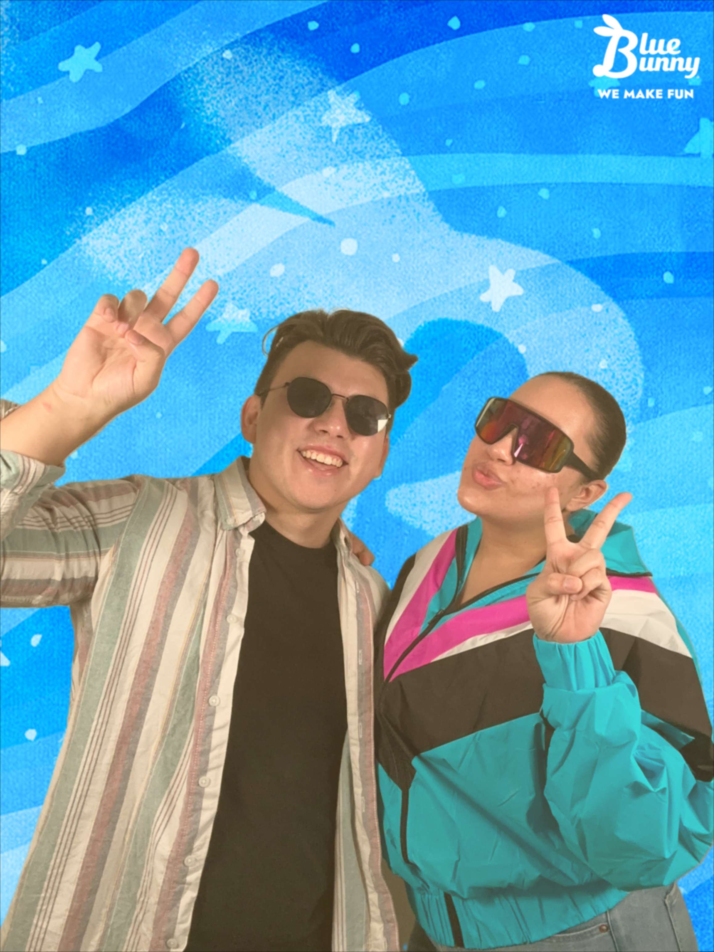 A young couple giving peace signs in sunglasses