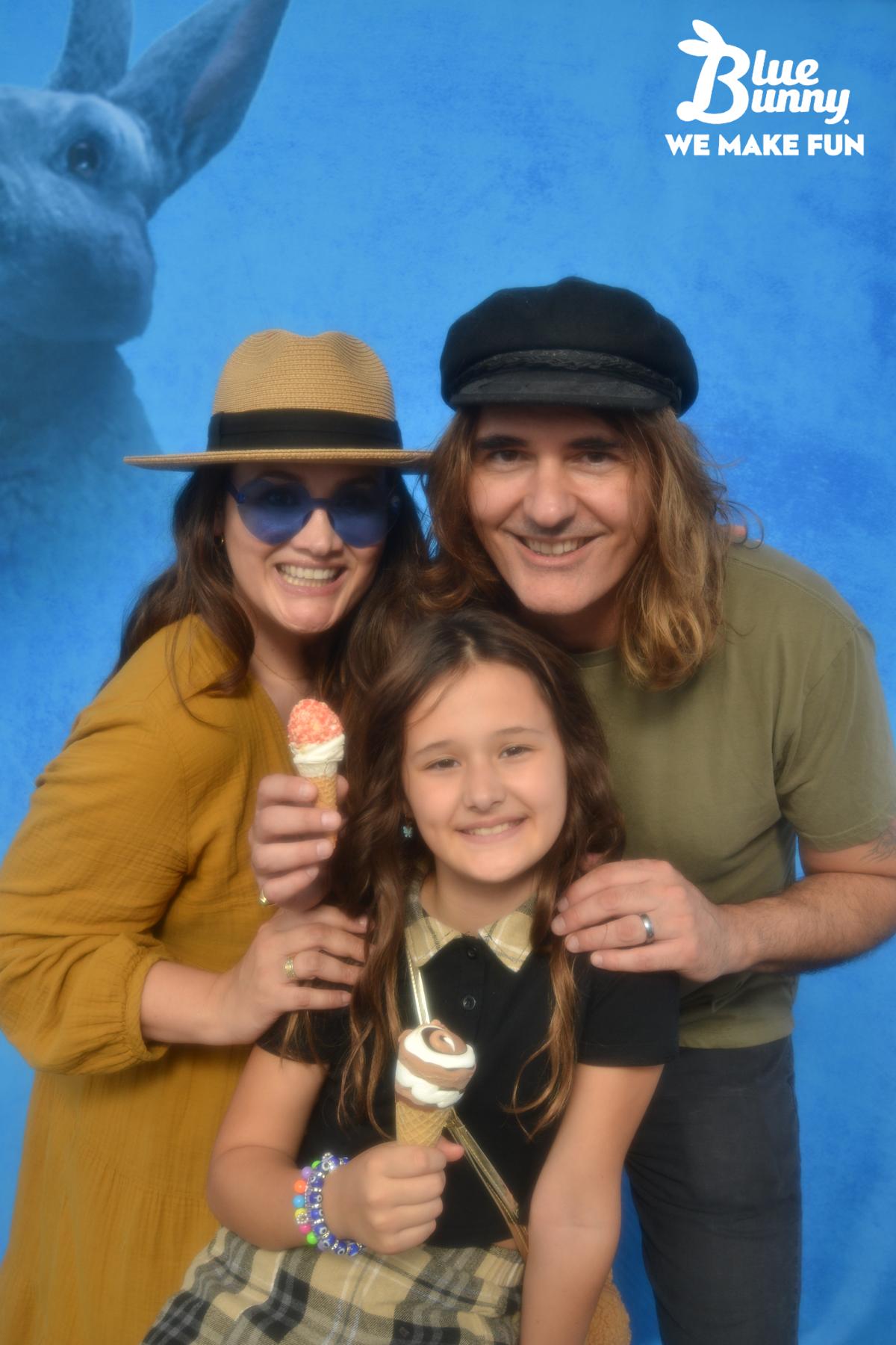 Family of three, with the parents in hats, holding Blue Bunny novelties