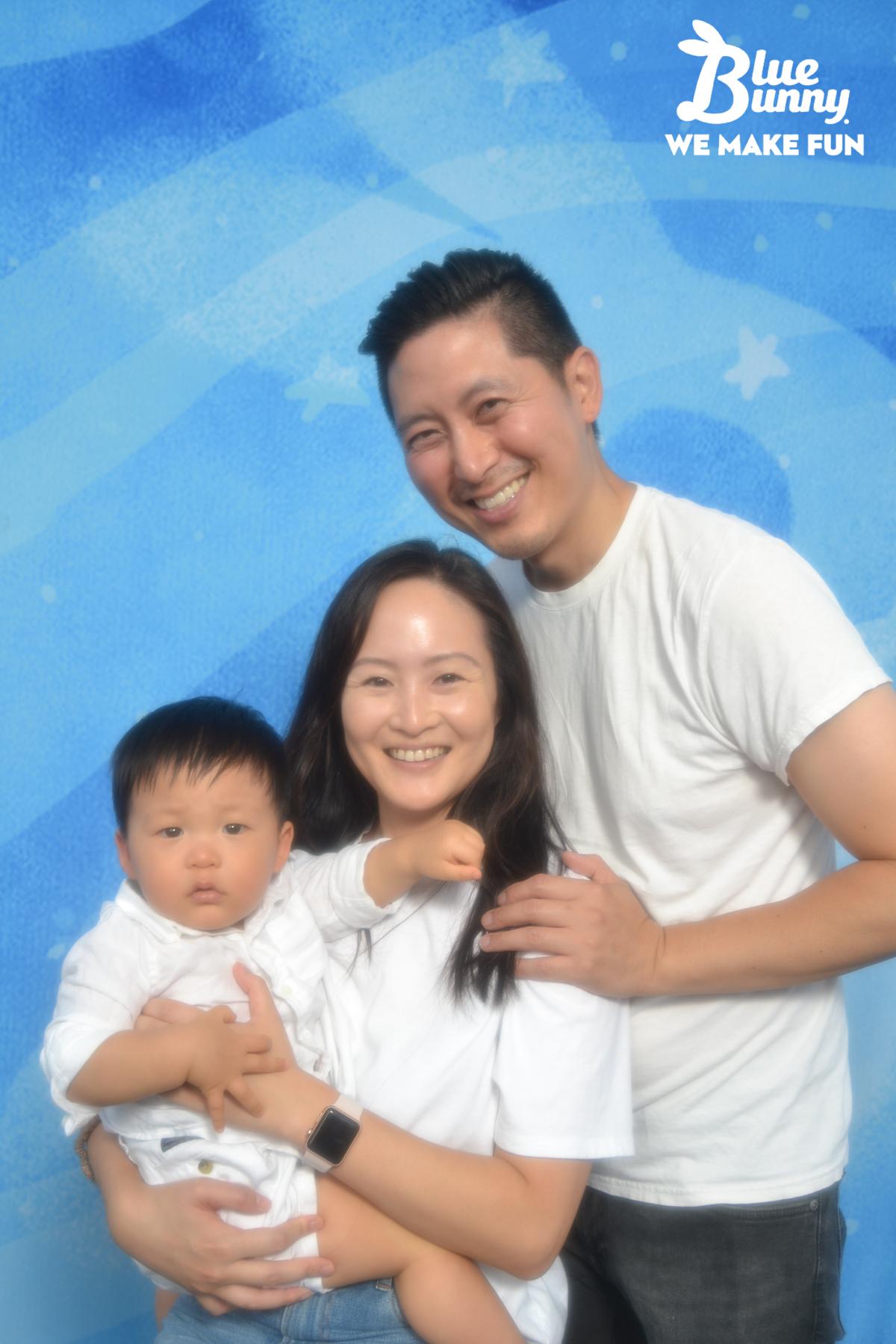 Two parents in white shirts holding their baby