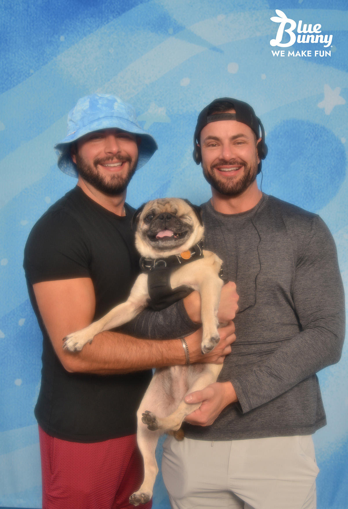 Two men in hats holding a pug