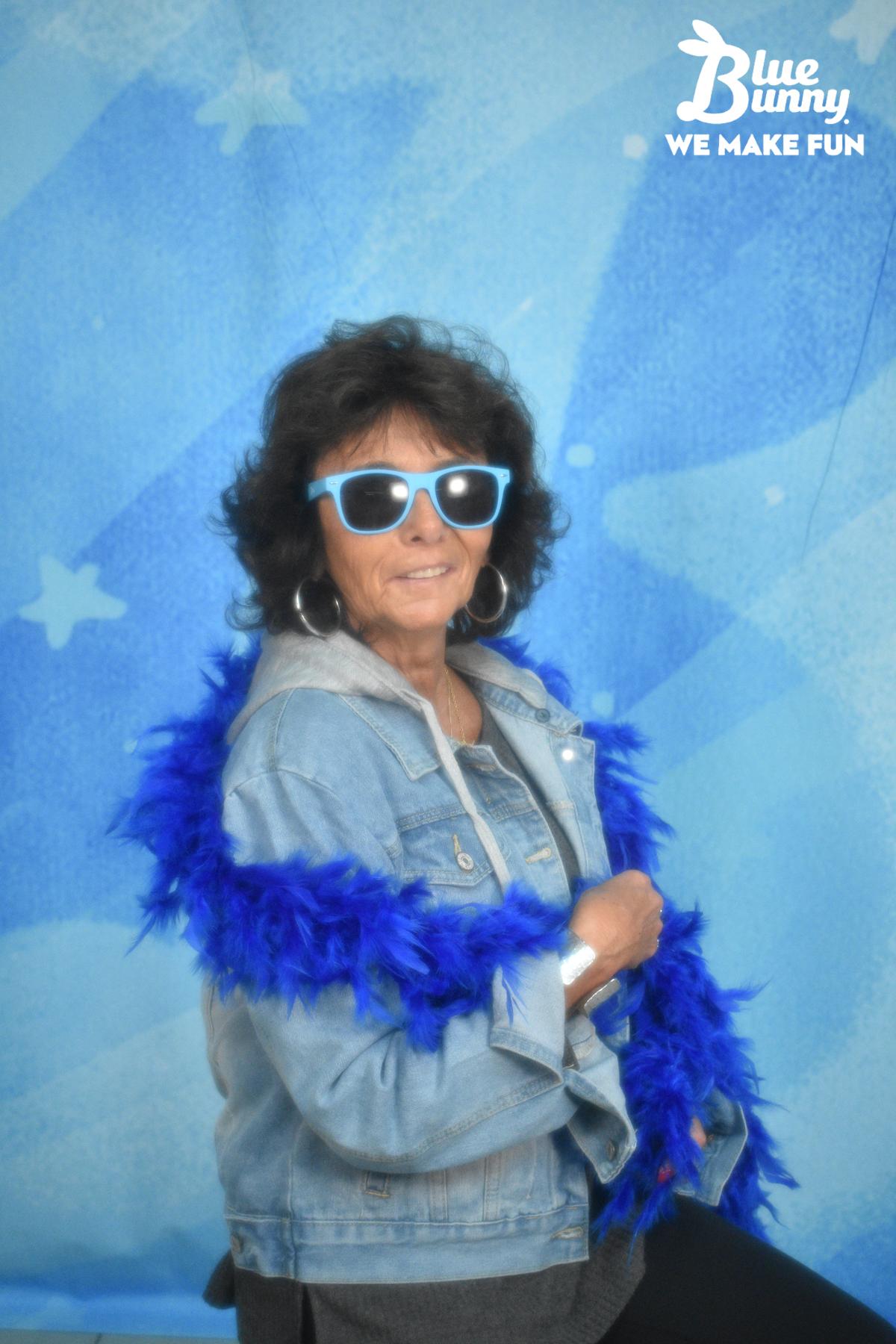 Older woman with a blue boa and blue sunglasses