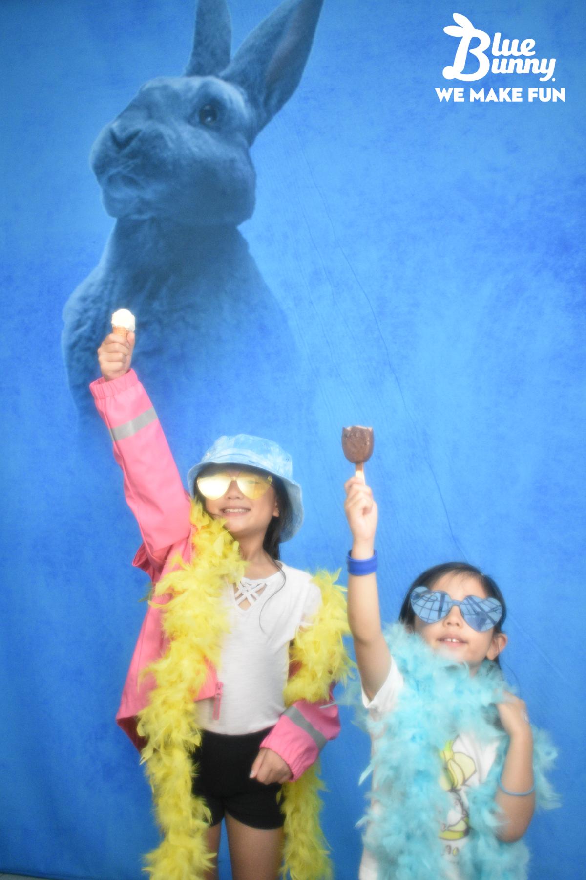 Two young girls holding mini icecream novelties in the air above their heads